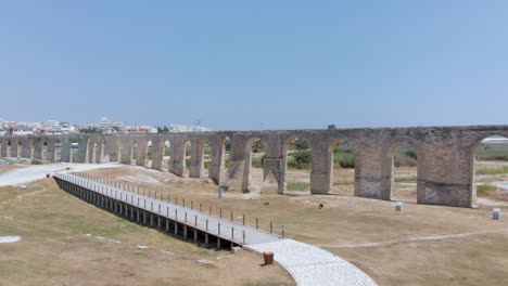 Wide-drone-shot-flying-up-over-the-Kamares-aqueduct-arches-to-reveal-local-resorts-and-buildings