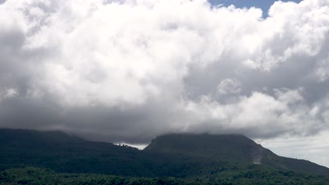 Fluffy-and-puffy-white-clouds-passing-over-the-tops-of-volcanoes-with-lush-green-vegetation-on-a-tropical-island-in-Asia-timelapse