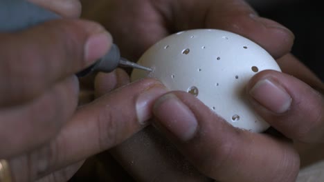 Closeup-of-a-person-carving-chicken-egg-using-a-drill-with-bare-hands