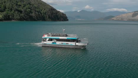 Pelorus-Mail-Boat,-Marlborough-Queen-Charlotte-Sounds,-New-Zealand-with-mountains-in-background--Aerial-Drone