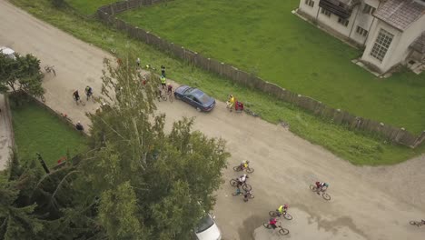 Aerial-shot-panning-over-cyclists-departing-a-rural-town-for-a-race-up-a-mountain-in-Romania
