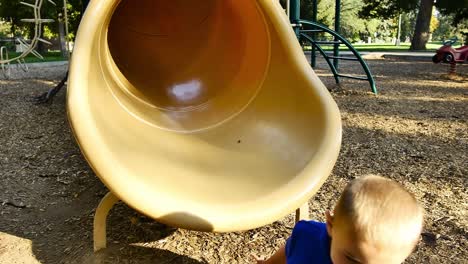 Little-blonde-boy-in-blue-shirt-falls-out-of-yellow-tube-slide
