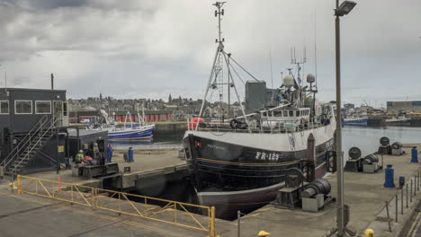 A-timelapse-of-a-fishing-ship-being-lifted-on-a-shiplfit-into-Fraserburgh-harbour-drydock-for-repair-work-to-be-carried-out,-mixture-of-sun-and-rain,-Fraserburgh,-Aberdeenshire