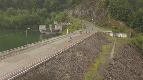 Aerial-view-of-a-group-of-bicyclist-biking-in-the-dam-at-Colibita-Lake-in-Romania-during-Tura-Cu-Copaci-race
