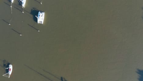 Overhead-shot-of-small-boats-floating-in-the-brown-Brisbane-River-casting-long-shadows