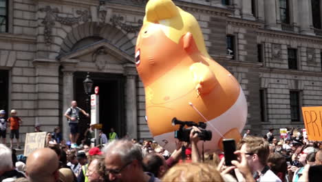 UK-July-2018---A-giant-balloon-depicting-President-Donald-Trump-as-an-angry,-orange-baby-in-a-nappy-floats-above-the-heads-of-thousands-of-cheering-protestors