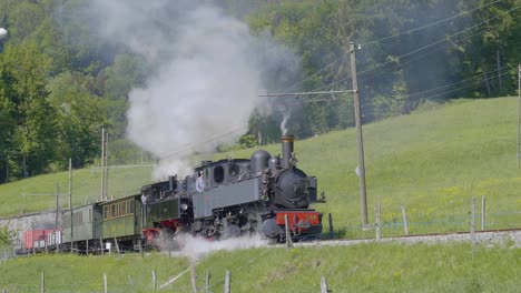 Two-steam-locomotives-with-railway-carriages-climbing-on-railroad-single-track-Blonay-Chamby-museum-track,-Switzerland