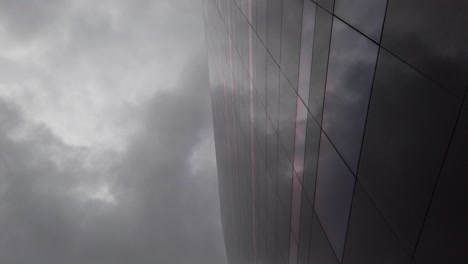 Cielo-Oscuro-Y-Nublado-Reflejado-En-Un-Edificio-De-Vidrio-Oscuro