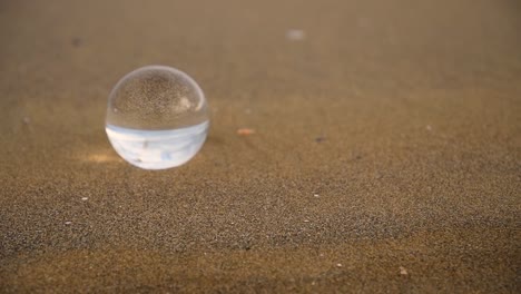 crystal-ball-reflecting-upside-down-with-zooming-looking-effect-on-a-beach-on-a-cloudy-and-windy-day-of-winter