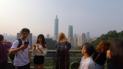 Blonde-girl-in-the-middle-of-asian-people-takes-a-picture-of-Taipei