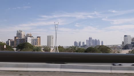 Conduciendo-Por-Una-Calle-Junto-A-Un-Enorme-Horizonte-De-Dubai