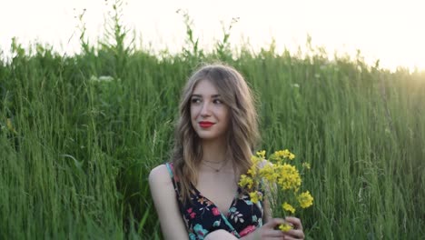 Woman-sat-in-grassy-field-with-bouquet-of-yellow-flowers
