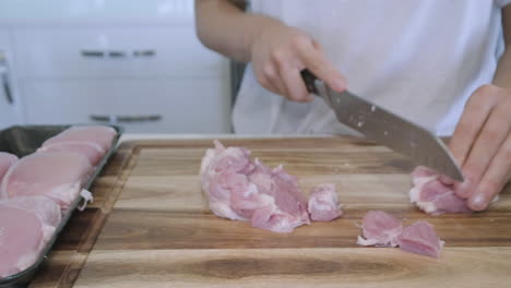 Sliding-shot-of-woman-in-kitchen-cutting-chicken-and-vegetables-for-Asian-stir-fry