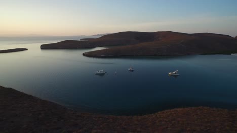 Aerial-shot-a-group-of-boats-in-a-calm-by-at-sunset,-Sea-of-Cortez,-Baja-California-Sur