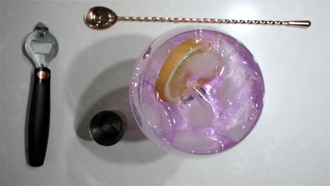 Blick-Von-Oben-Auf-Ein-Großes-Ballonglas-Mit-Stiel,-Während-Die-Orangenscheibe-Einem-Köstlichen-Rosafarbenen-Gin-Tonic-Cocktail-Den-Letzten-Schliff-Verleiht