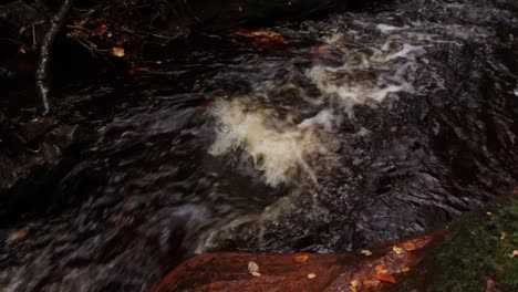 Scottish-river-creek-flowing-in-slow-motion-in-the-fall-autumn-season-at-finnich-glen-devils-pulpit-in-the-united-kingdom