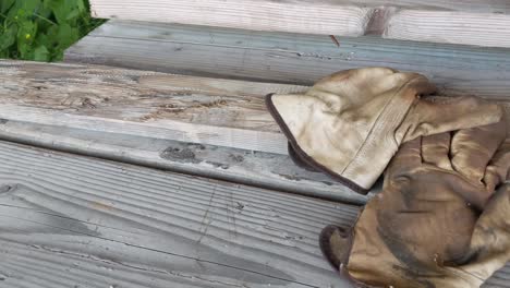 A-pair-of-old-worn-leather-work-gloves-laying-on-a-bunk-of-weathered-two-by-four-boards