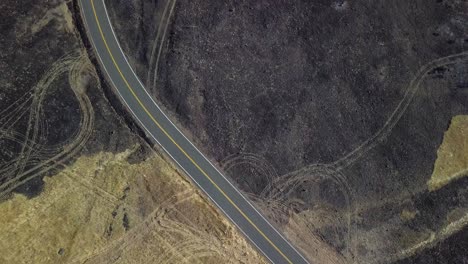 Drone-Panorámico-Desde-El-Corte-De-La-Carretera-A-Través-Del-Campo-Dañado-Por-El-Fuego-Para-Revelar-Los-Daños-Causados-Por-El-Fuego-En-El-Condado-De-Lassen-Del-Norte-De-California