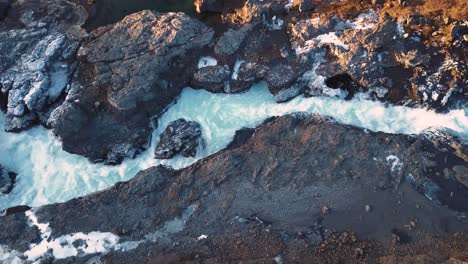 Drone-with-cinematic-movements-shows-beautiful-icelandic-waterfall,-Hraunfossar,-in-sunset-light-from-multiple-angles