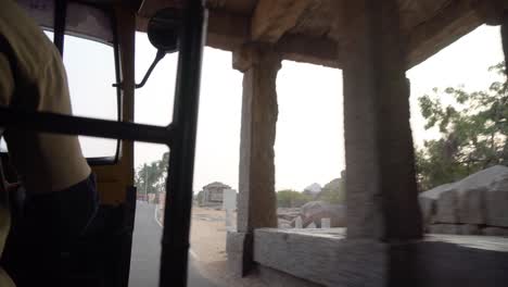 Inside-auto-rickshaw-view-of-stone-temple-ruins,-Hampi,-India,-Karnakata
