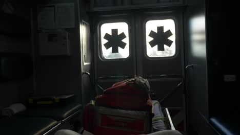 View-from-the-inside-of-the-back-of-an-ambulance-as-it-drives-on-a-road-with-emergency-medical-symbol
