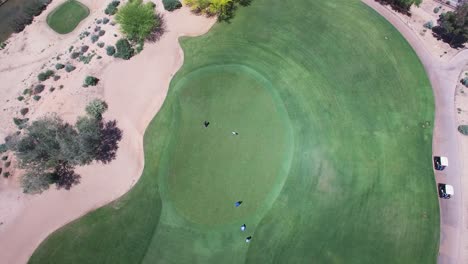 Aerial-slow-ascent-over-a-green-where-a-group-of-golfers-watch-as-one-of-them-tries-and-misses-a-long-putt,-Westin-Kierland-Golf-Course,-Scottsdale,-Arizona