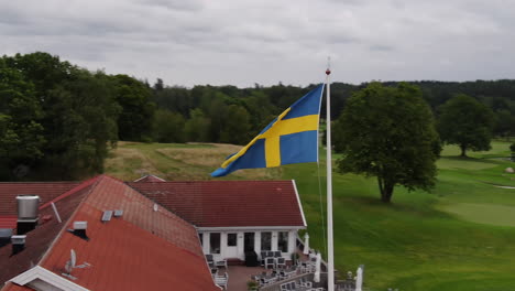 The-Swedish-flag-waving-in-the-sky-on-a-cloudy-day-at-golf-course