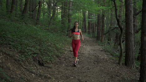 Fitness-Frau-Joggt-Einen-Waldweg-Hinunter,-Vorderansicht