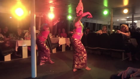 Two-women-performing-a-traditional-dance-inside-a-cruise-ship-with-an-audience-in-Bali,-Indonesia