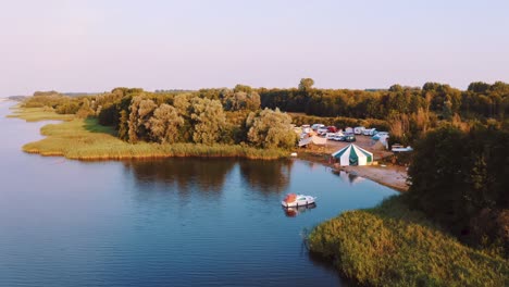 Aerial-drone-reveal-Wildeburg-Festival-Camp-Site-next-to-lake,-early-morning