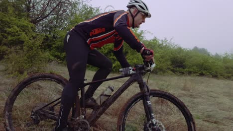 Tracking-Pan,-mountain-bike-rider-on-countryside-trail,-foggy-day