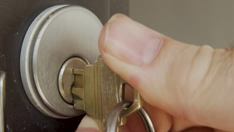 Macro-shot-of-inserting-key-into-a-lock-and-unlocking-a-door