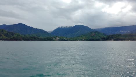 4K-Hawaii-Kauai-Boating-on-ocean-floating-right-to-left-with-mountains-and-clouds-with-boat-spray-in-foreground