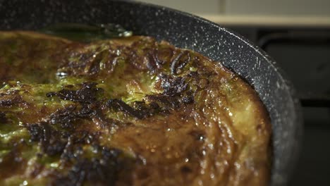EXTREME-CLOSE-UP-ZOOM-IN-Beautiful-shot-of-an-authentic-italian-Frittata-cooking-in-a-large-pan-with-bubbling-fat-coming-from-the-sides