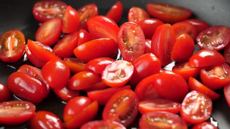 Close-up-shot-of-heated-pan-with-olive-oil-and-putting-halved-cherry-tomatoes-in
