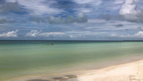 Kamerafahrt-Am-Von-Palmen-Gesäumten-Karibischen-Strand-Mit-Menschen,-Die-Das-Klare-Wasser-Genießen