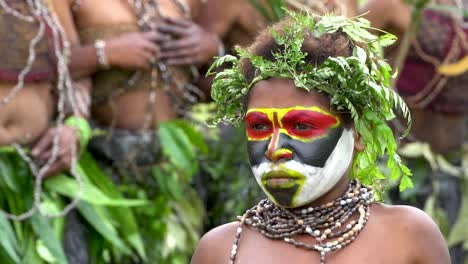 Young-boy-looking-as-dancers-jump-in-background,-slow-motion,-Papua-New-Guinea