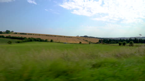 Die-Schöne-Grüne-Englische-Britische-Landschaft,-Die-An-Der-Seite-Eines-Autos-Vorbeifährt,-Das-In-Zeitlupe-Die-Malerischen-Landstraßen-Hinunterfährt-Und-Weizenfelder-Und-Das-Ackerland-Des-Britischen-Gloucestershire-Zeigt