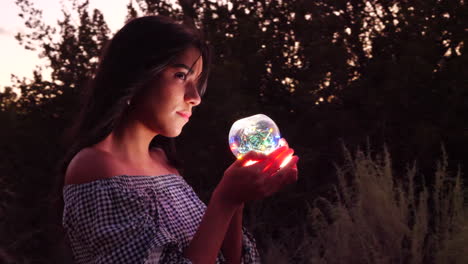 A-beautiful-woman-sorcerer-wandering-in-a-fantasy-landscape-with-a-magic-spiritual-orb-glowing-in-illuminated-light
