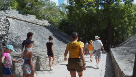 Static-Wide-shot-of-tourists-walking-through-the-Muyil-archaeological-site,-Quintana-Roo,-Mexico