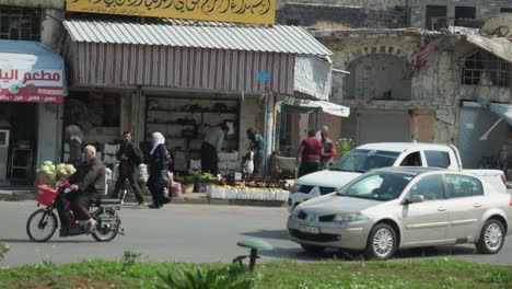 Slow-motion,-cars-passing-and-people-walking-along-the-street-of-Homs-City