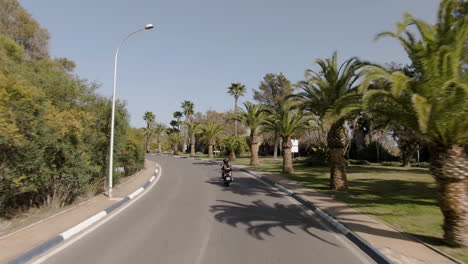 Wide-aerial-of-a-couple-riding-on-motorbike-in-Marbella-in-summertime