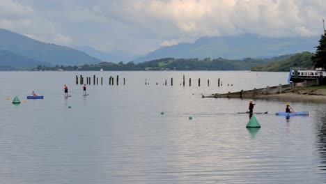Active-lifestyle-in-Scotland,-people-rowing-on-paddleboards-on-the-Loch-Lomond-in-Scotland