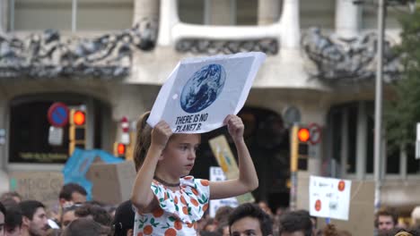 Kleines-Mädchen-Hält-Protestschild-Gegen-Den-Klimawandel-über-Der-Menge,-Die-Auf-Schultern-Reitet