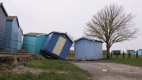 Three-beach-huts-moved-off-their-footings-and-piled-next-to-tree