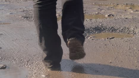 Feet-walking-across-muddy-potholes-on-road
