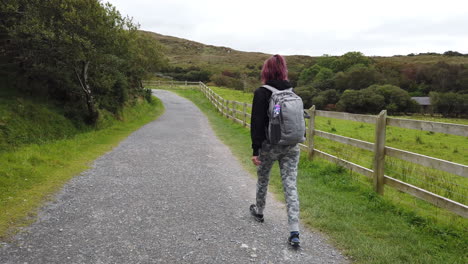 Dolly-shot-of-a-Girl-walking,-hiking-in-Connemara-National-Park-on-the-trail-to-diamond-hill-in-Ireland-4K