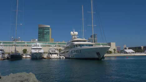 Yachts-including-Dum-Luck-and-New-Secret-parked-on-pier-alongside-the-Hilton-hotel-and-convention-center,-Left-locked-panning-shot