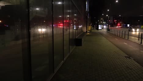 Walking-in-the-city-at-night,-reflection-in-the-glass-wall