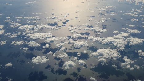Aerial-top-down-of-group-of-clouds-reflecting-shadows-on-sea